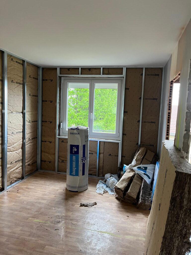 Pièce avec fenêtre, doublage en cours et matériel de chantier