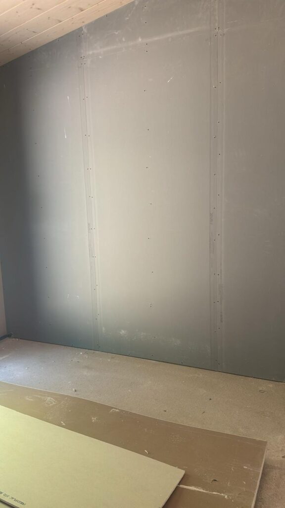 Mur en cours de doublage avec panneaux posés au sol