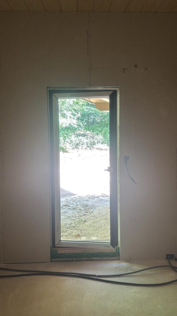 Pièce en travaux avec porte-fenêtre étroite et câbles au sol