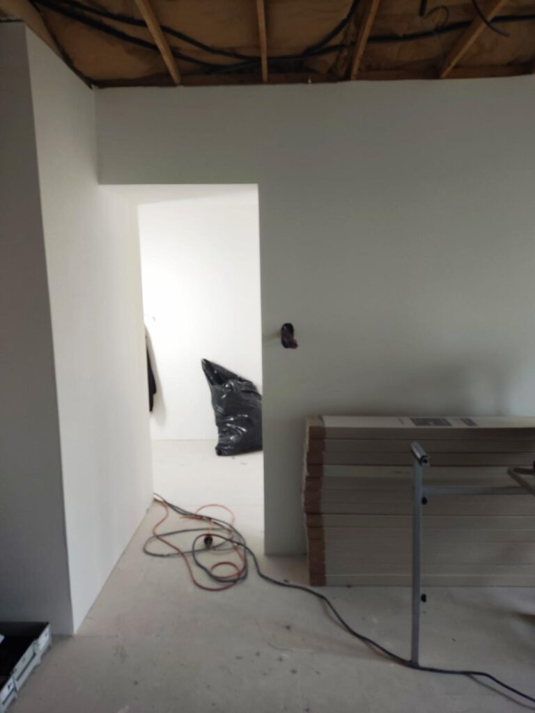 Entrée d'une pièce blanche avec plafond ouvert en cours de rénovation