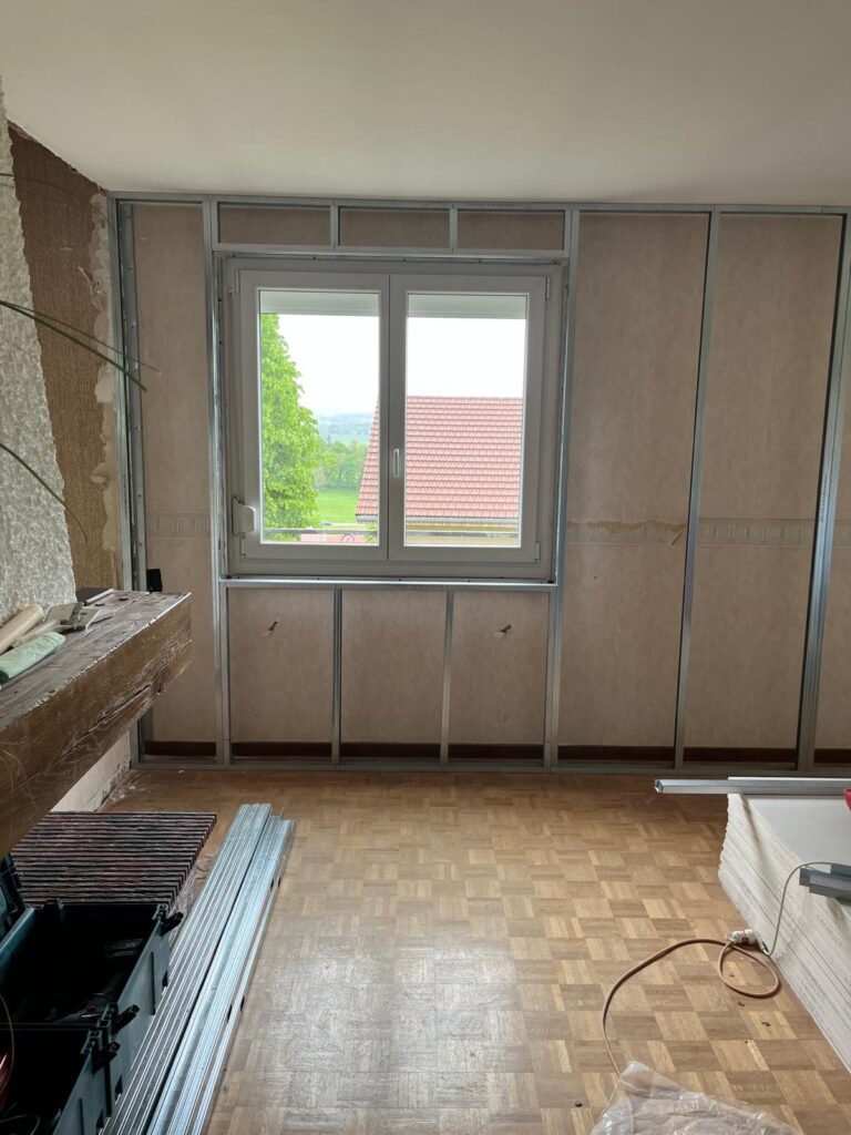 Fenêtre et mur isolé au-dessus d'un ancien parquet, chantier de rénovation