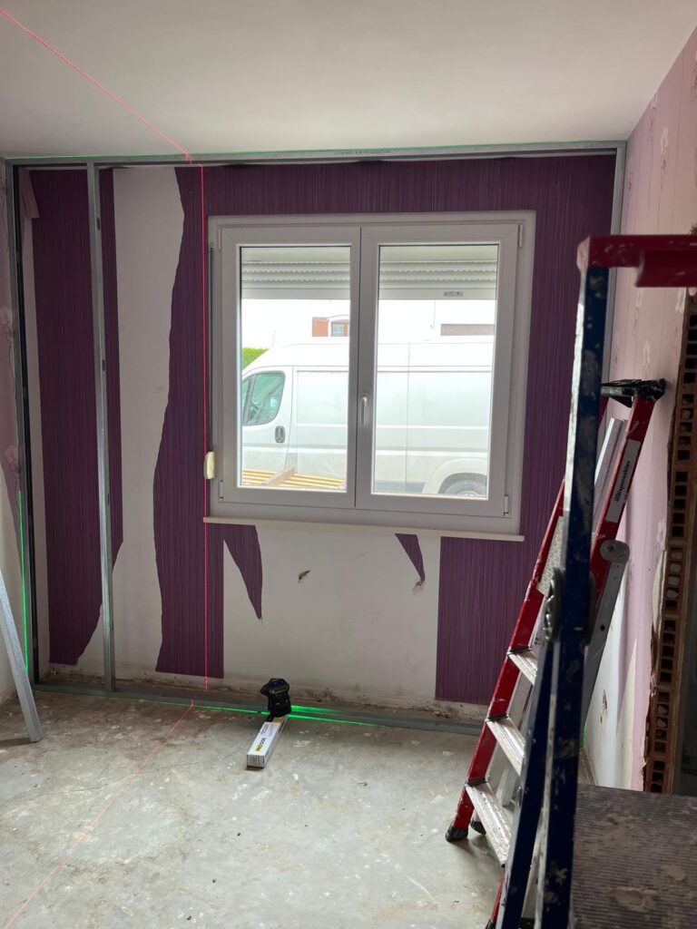 Chambre en travaux avec fenêtre, rideaux violets et escabeau