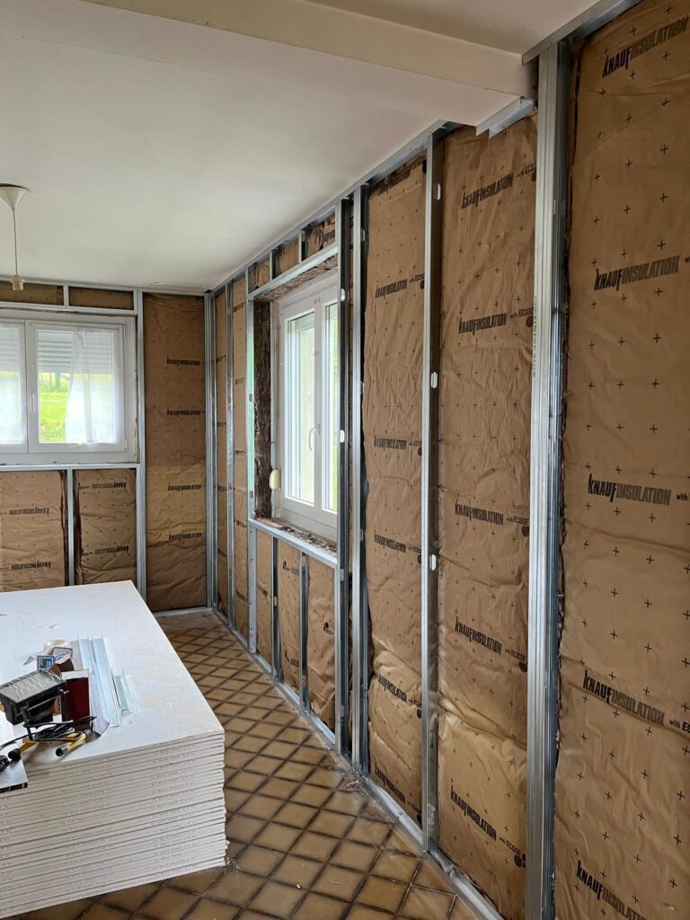 Pièce aux rails métalliques de doublage et plaques de plâtre empilées