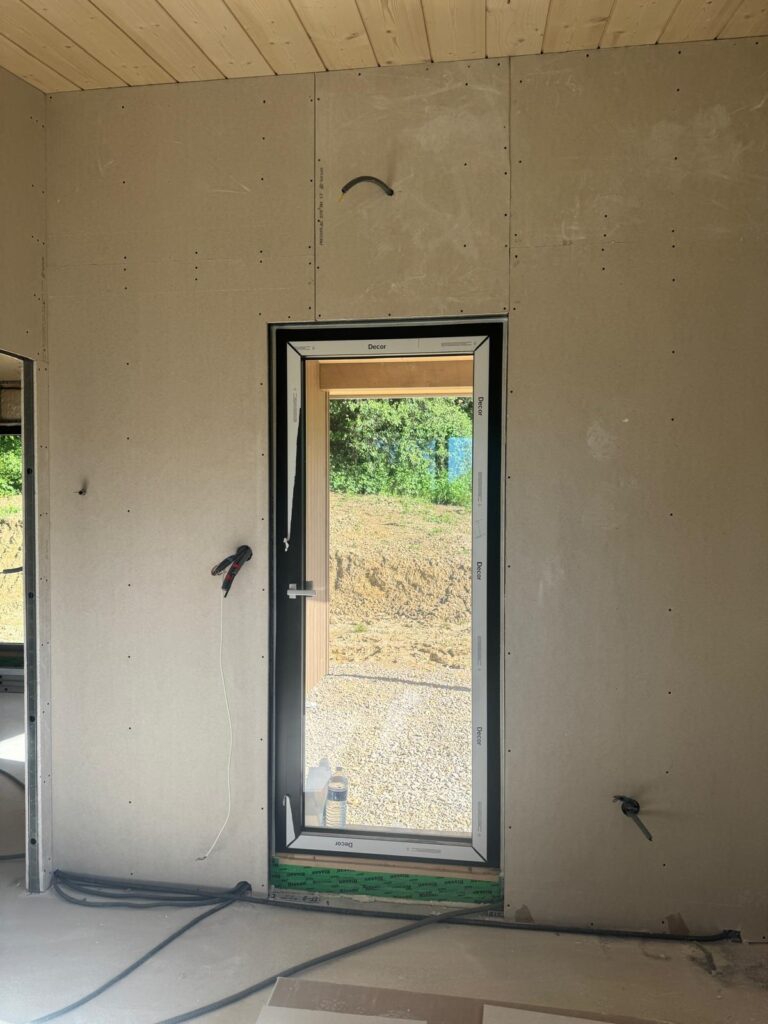 Pièce avec porte-fenêtre vitrée et murs en plaques de plâtre