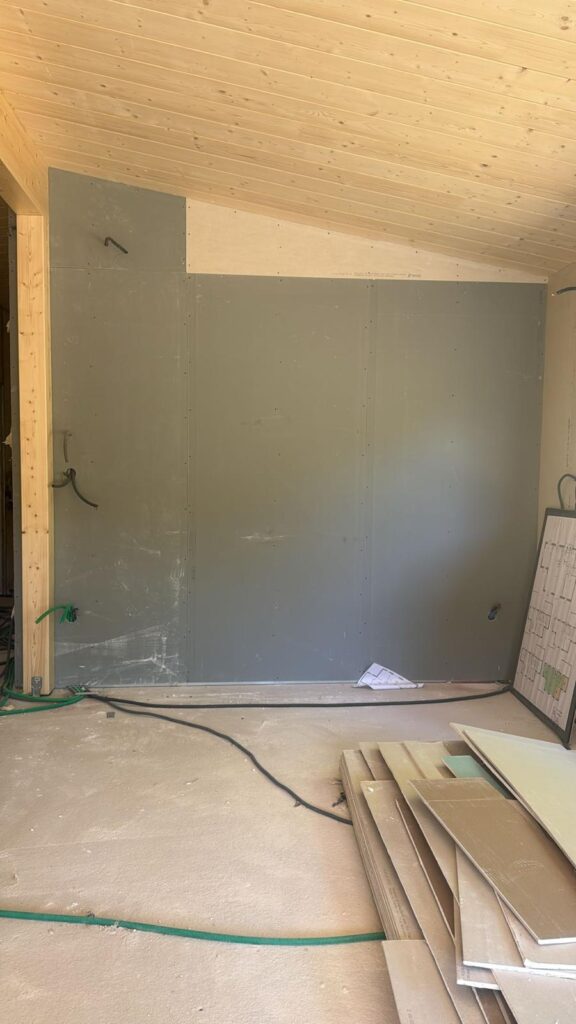 Mur de plâtre gris et sol en préparation sous un plafond lambrissé