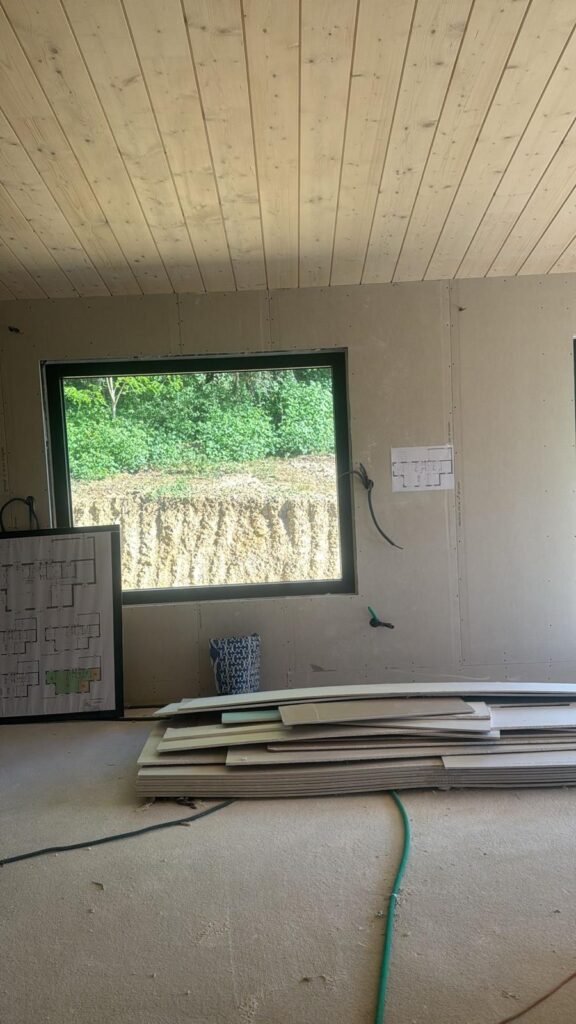 Pièce au plafond lambrissé et fenêtre noire, chantier de rénovation intérieure