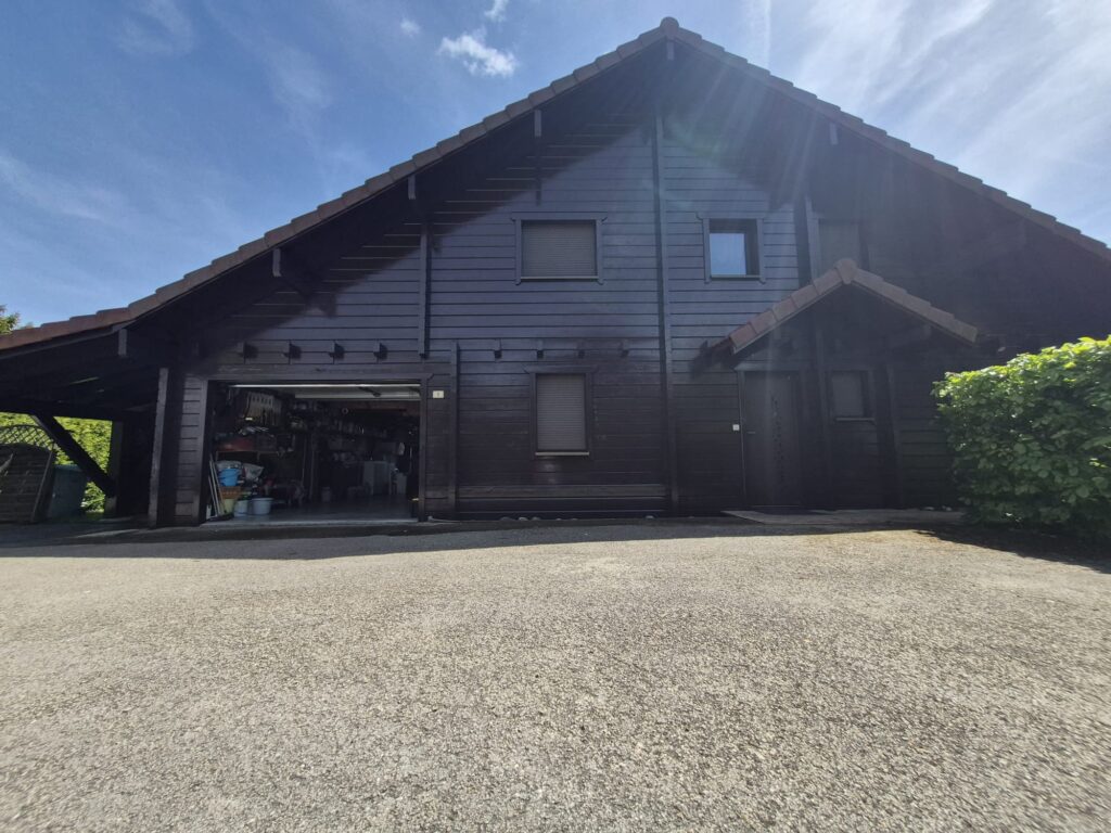 Chalet en bois sombre et son allée gravillonnée