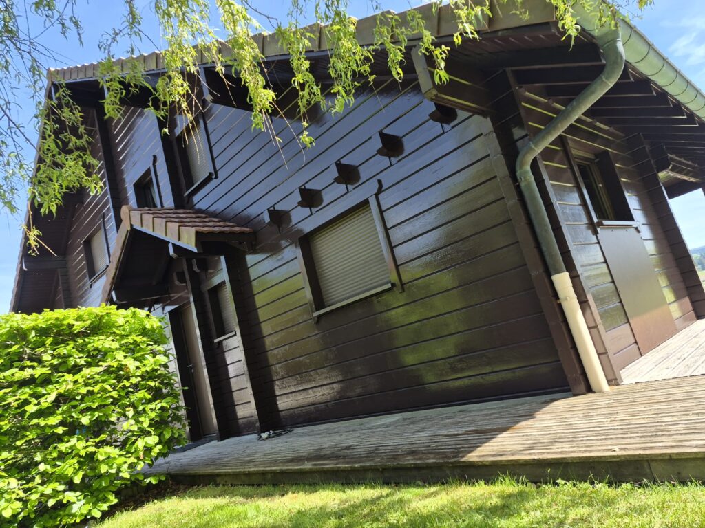 Angle d'un chalet en bois avec haie et terrasse