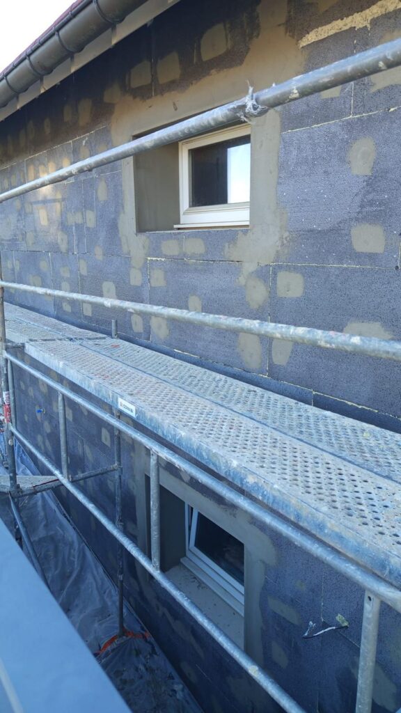 Isolation extérieure de façade : panneaux isolants gris au-dessus du plancher d'échafaudage