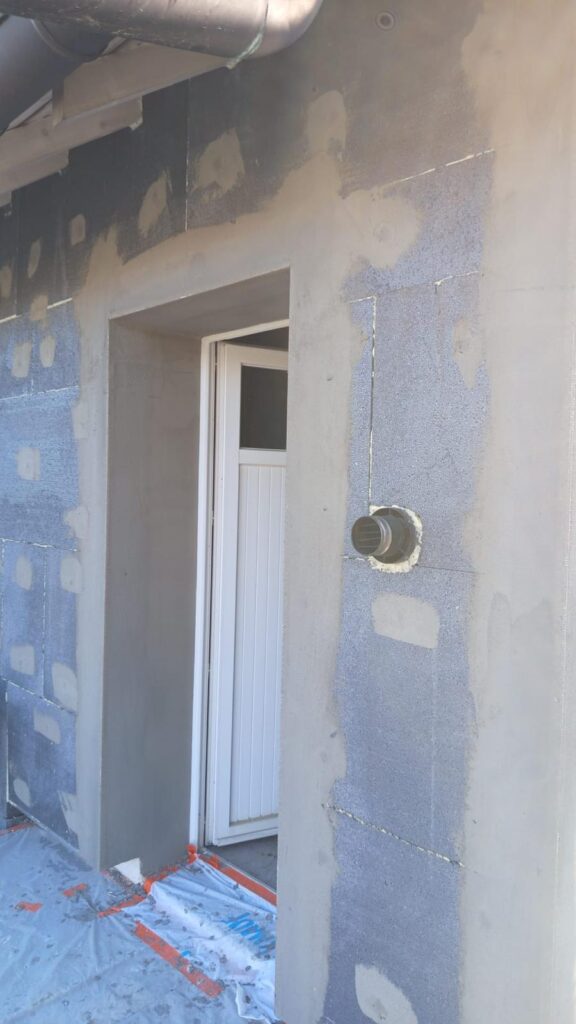 Isolation extérieure de façade : porte blanche et passage de ventilation dans l'isolant