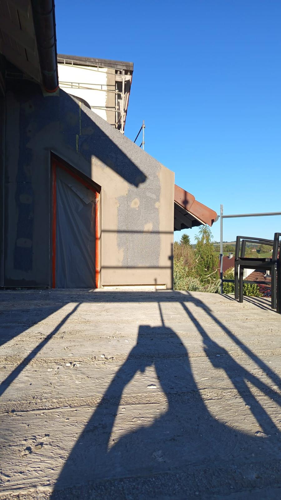 Isolation extérieure de façade : mur protégé par une bâche, terrasse et mobilier de jardin