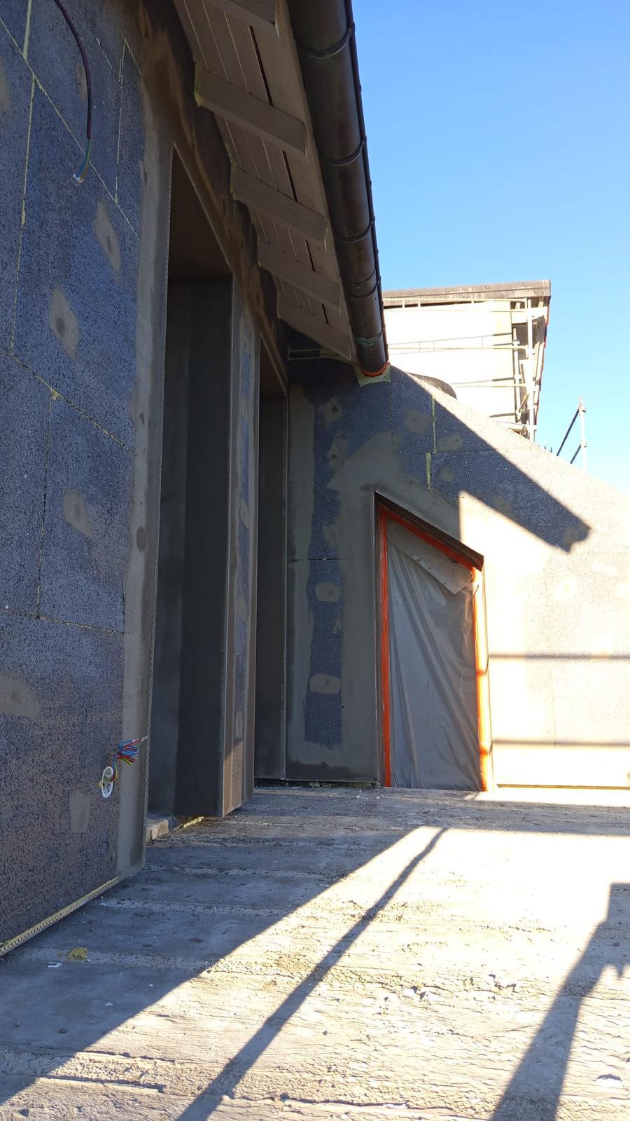 Isolation extérieure de façade : angle de mur avec panneaux isolants gris et fenêtre protégée