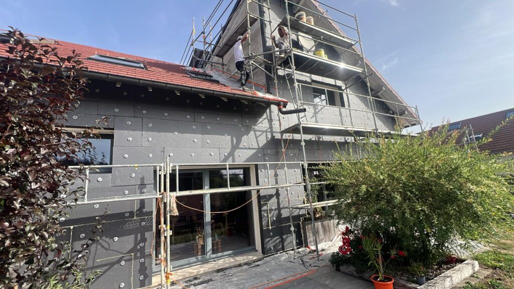 Isolation extérieure de façade : maison sous échafaudage et jardin fleuri