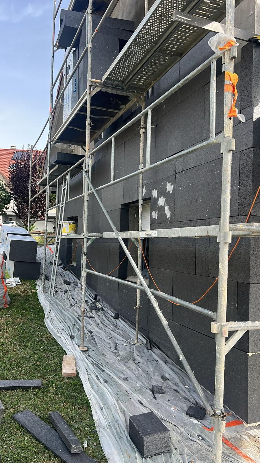 Isolation extérieure de façade : panneaux isolants noirs sous échafaudage