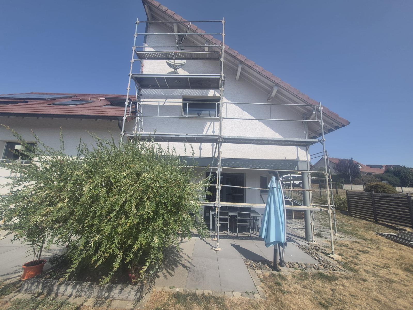 Isolation extérieure de façade : pignon de maison sous échafaudage derrière un arbuste